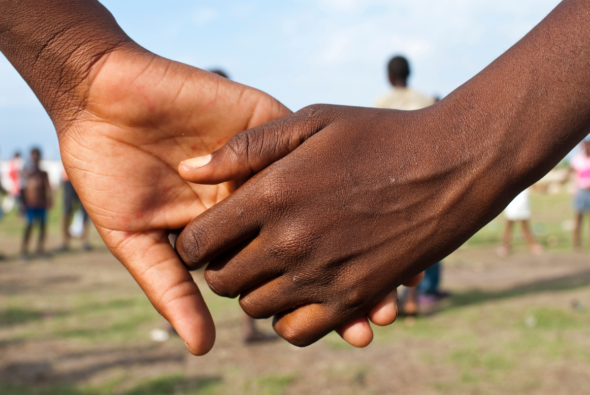 Close-up of two people holding hands in a field